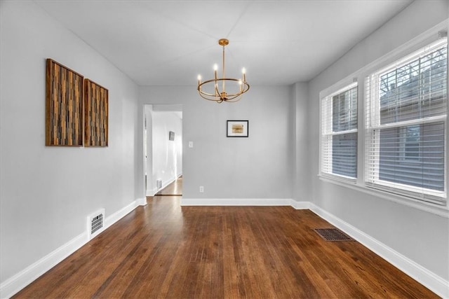 empty room with baseboards, visible vents, and a notable chandelier