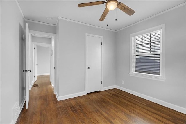 unfurnished bedroom with crown molding, dark wood-style flooring, and baseboards