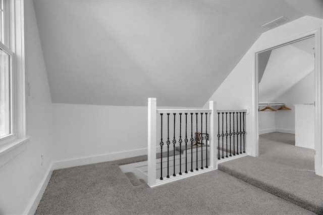 additional living space with carpet, visible vents, lofted ceiling, and baseboards