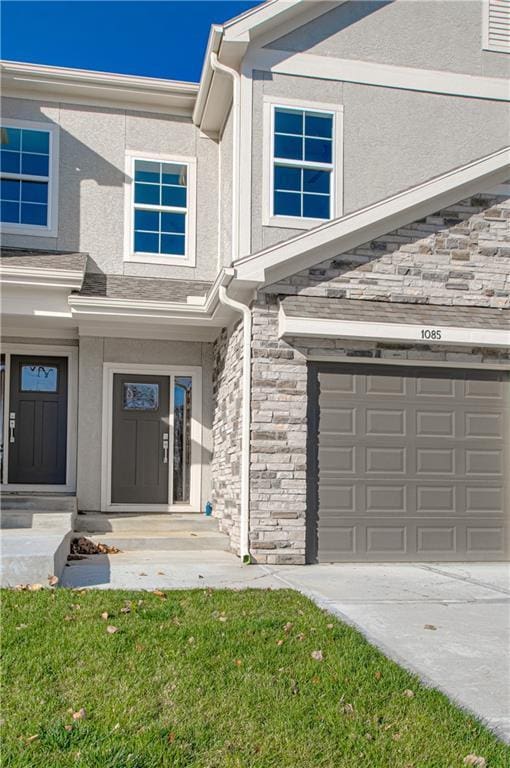 view of exterior entry with a lawn and a garage