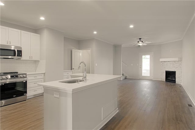 kitchen with a center island with sink, white cabinets, sink, dark hardwood / wood-style floors, and appliances with stainless steel finishes