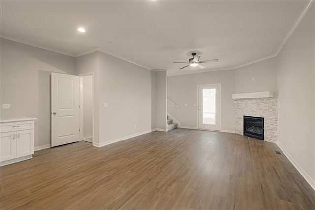 unfurnished living room with a stone fireplace, ceiling fan, ornamental molding, and hardwood / wood-style flooring