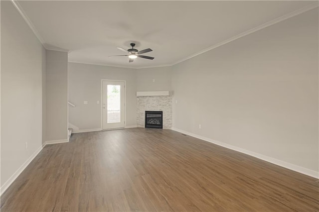 unfurnished living room with ceiling fan, a fireplace, crown molding, and dark wood-type flooring