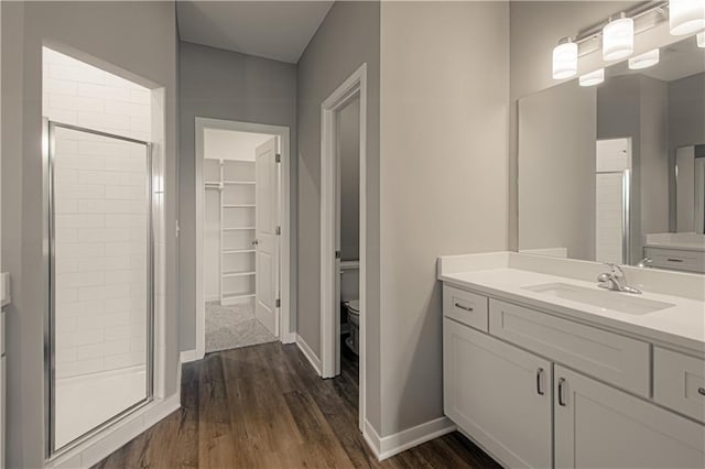 bathroom with a shower with door, vanity, wood-type flooring, and toilet