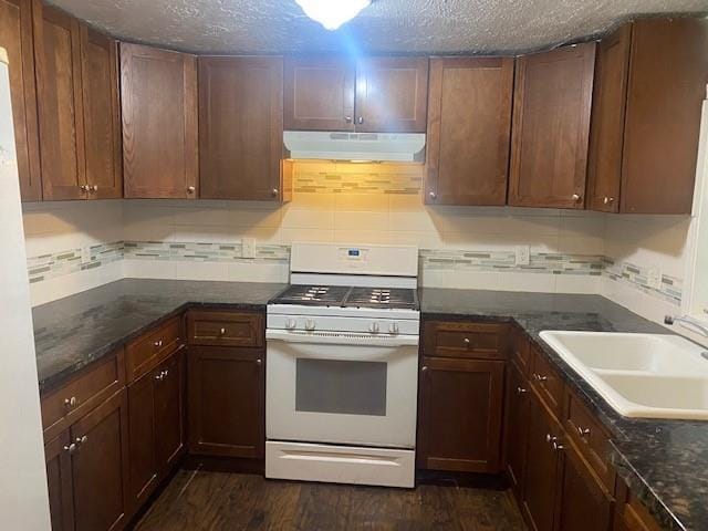 kitchen featuring white appliances, dark wood-type flooring, sink, a textured ceiling, and tasteful backsplash