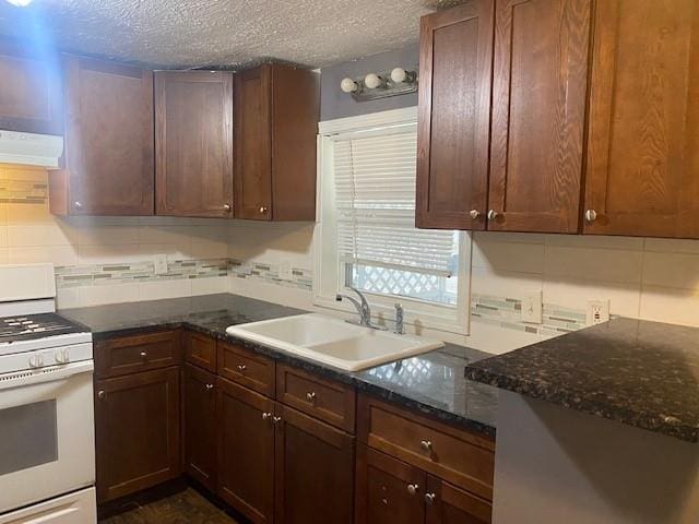 kitchen featuring sink, white range oven, backsplash, dark stone countertops, and extractor fan