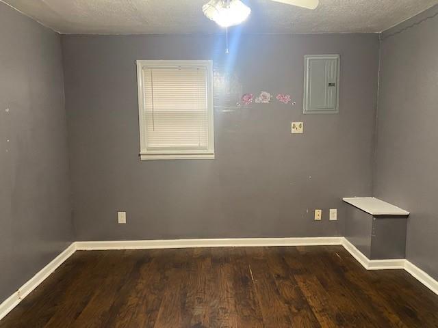 spare room featuring a textured ceiling, dark hardwood / wood-style flooring, electric panel, and ceiling fan