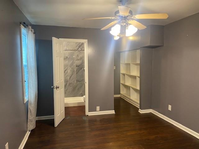 unfurnished bedroom with ceiling fan and dark wood-type flooring