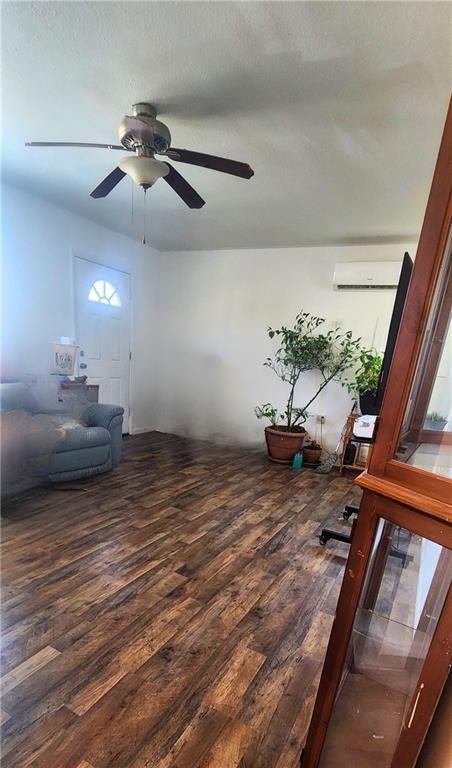 unfurnished room with a wall mounted air conditioner, dark hardwood / wood-style floors, and ceiling fan