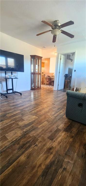 living room with a wall unit AC, dark hardwood / wood-style floors, and ceiling fan