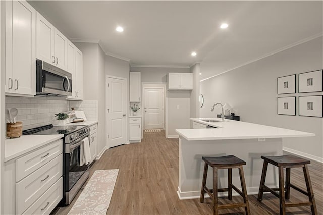 kitchen featuring a kitchen bar, light hardwood / wood-style flooring, white cabinets, and stainless steel appliances