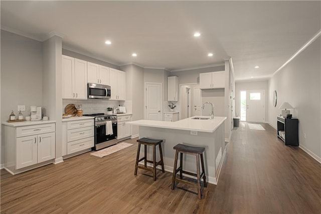 kitchen featuring white cabinets, stainless steel appliances, and a center island with sink