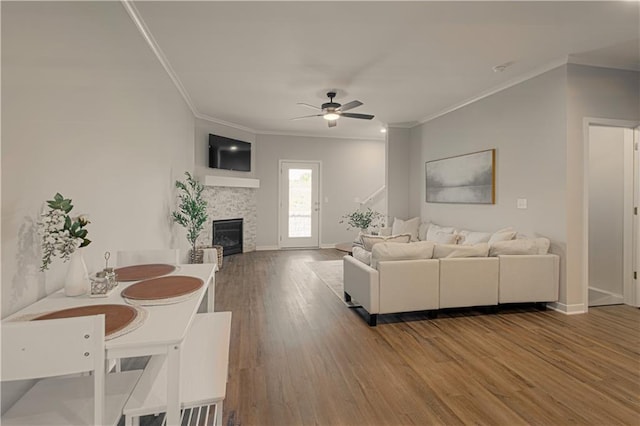 living room featuring hardwood / wood-style floors, ceiling fan, ornamental molding, and a fireplace