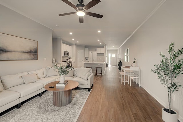 living room featuring ceiling fan, wood-type flooring, and ornamental molding