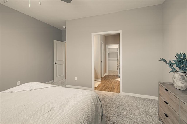 bedroom featuring light carpet, a walk in closet, a closet, and ceiling fan