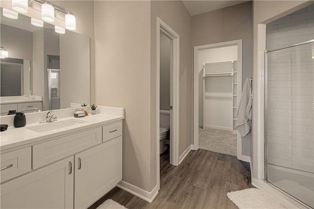 bathroom with vanity, wood-type flooring, a shower with shower door, and toilet