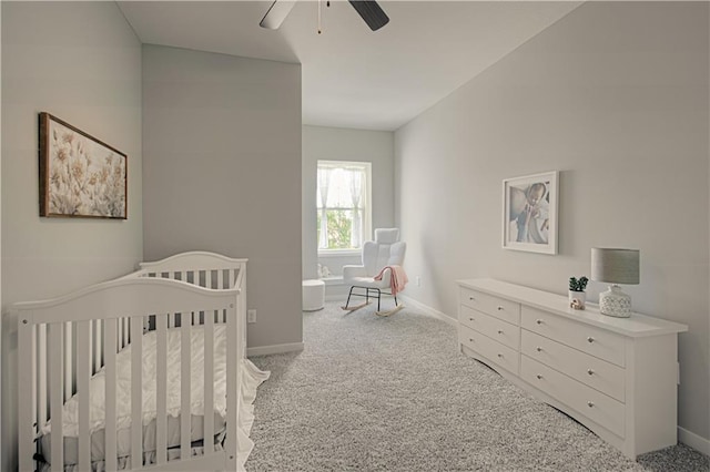 bedroom with ceiling fan, a crib, and light carpet