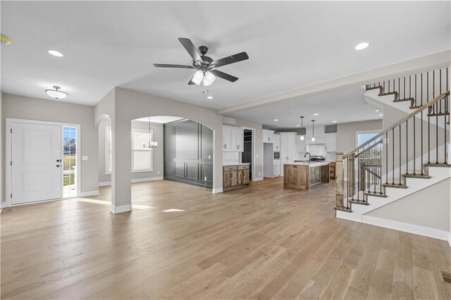 18580 W 169th Ter, Olathe, KS 66062 - unfurnished living room with arched walkways, light wood-style floors, plenty of natural light, ceiling fan, and recessed lighting