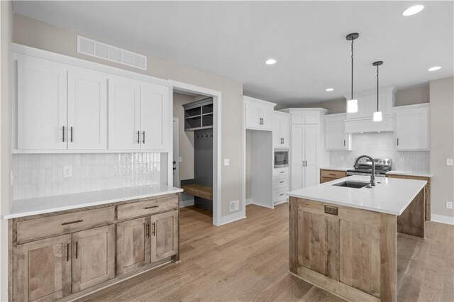 18580 W 169th Ter, Olathe, KS 66062 - kitchen with stainless steel microwave, backsplash, light wood-type flooring, recessed lighting, and an island with sink