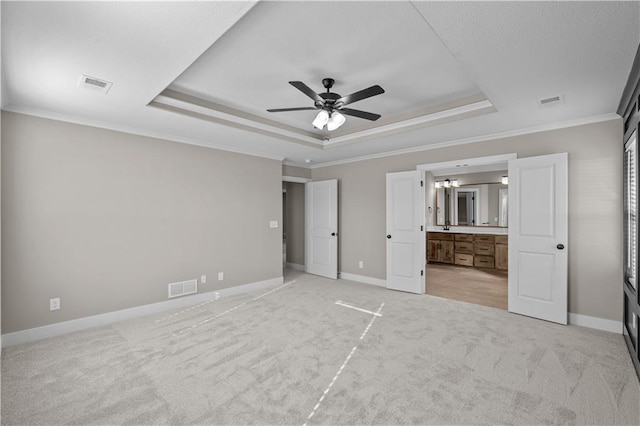 unfurnished bedroom with light carpet, ensuite bathroom, a raised ceiling, crown molding, and ceiling fan