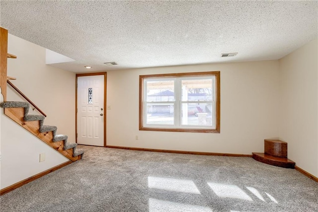 carpeted foyer entrance with a textured ceiling