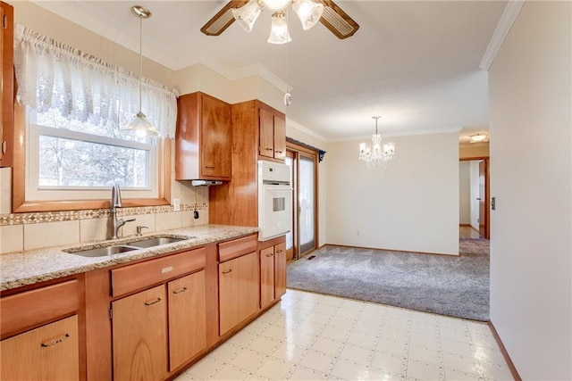 5032 NE 57th Ter, Kansas City, MO 64119 - kitchen with white oven, a sink, plenty of natural light, a ceiling fan, and crown molding