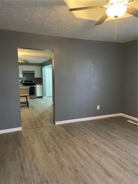 spare room featuring ceiling fan, wood-type flooring, and a textured ceiling