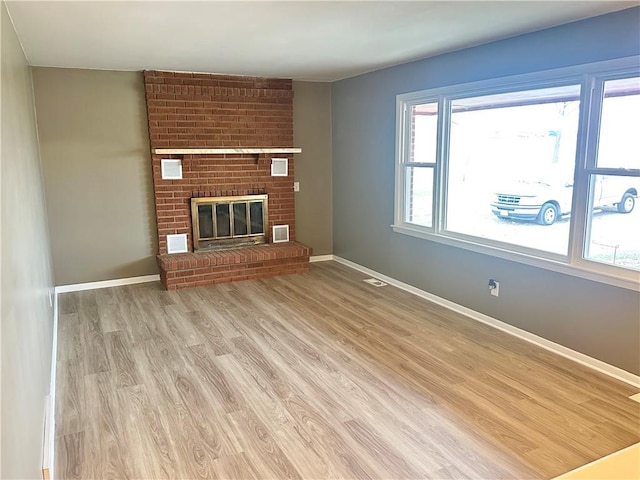 unfurnished living room with a fireplace, a wealth of natural light, and light hardwood / wood-style flooring