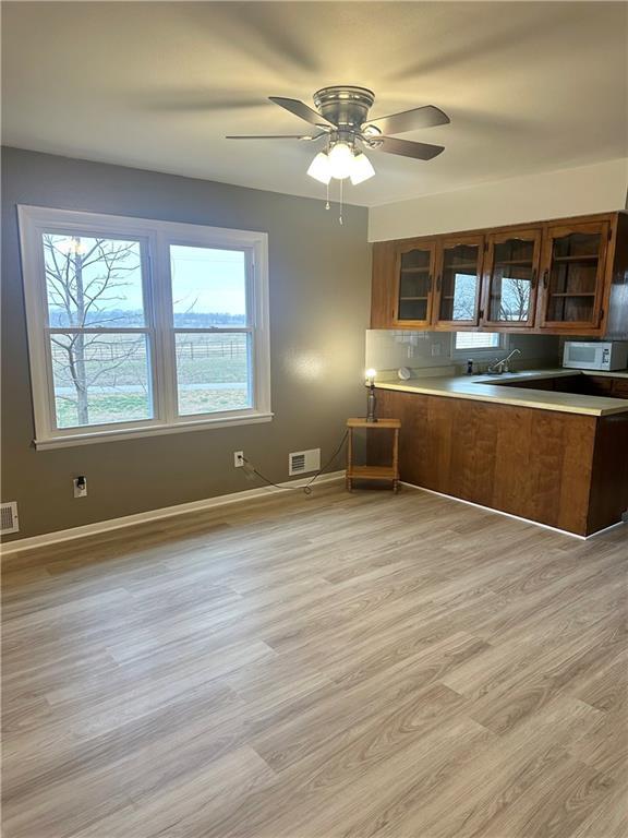 kitchen with ceiling fan, decorative backsplash, and light hardwood / wood-style flooring