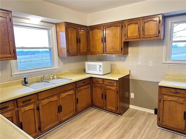 kitchen featuring decorative backsplash, light hardwood / wood-style flooring, and sink