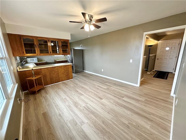 kitchen with light hardwood / wood-style flooring, ceiling fan, white range oven, kitchen peninsula, and stainless steel refrigerator