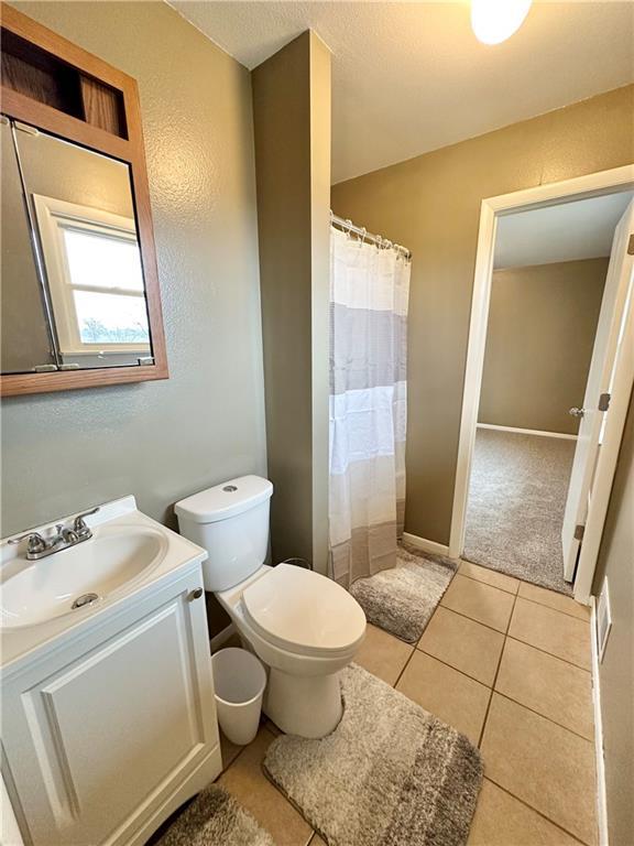 bathroom with toilet, vanity, and tile patterned floors