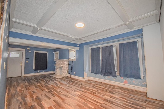 unfurnished living room featuring coffered ceiling, a fireplace, a textured ceiling, beam ceiling, and wood-type flooring