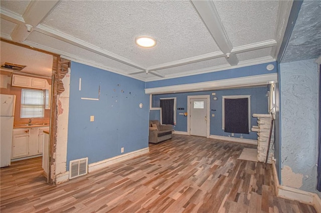 unfurnished living room with sink, coffered ceiling, beamed ceiling, wood-type flooring, and a textured ceiling