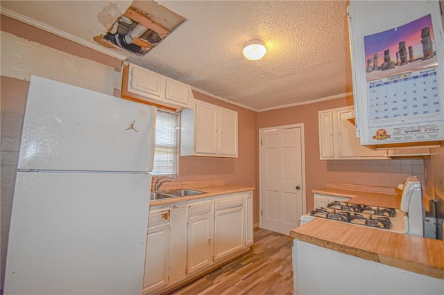 kitchen with white cabinetry, sink, light hardwood / wood-style floors, white appliances, and ornamental molding