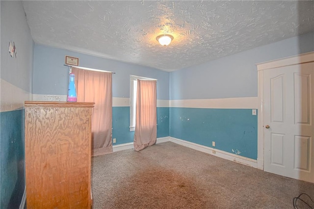 unfurnished room with a textured ceiling and carpet floors