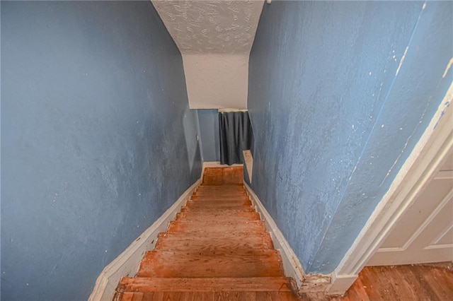 stairway featuring a textured ceiling and hardwood / wood-style flooring