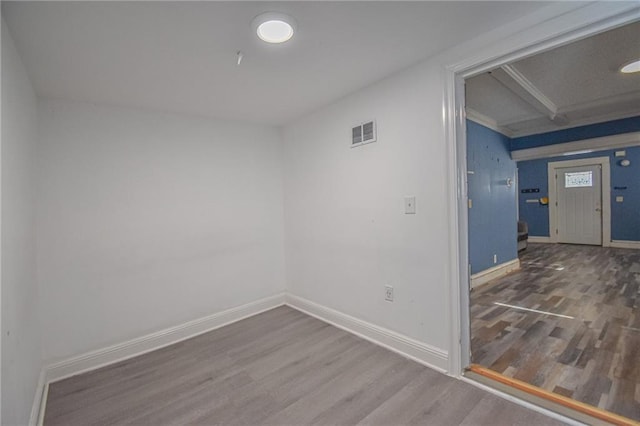 empty room with hardwood / wood-style flooring and beamed ceiling