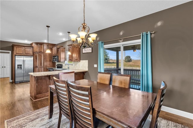 dining room featuring sink, dark wood-type flooring, and a chandelier