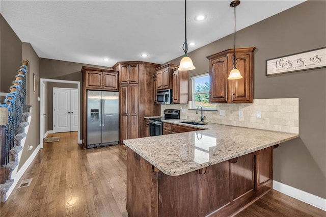 kitchen with sink, pendant lighting, decorative backsplash, a breakfast bar, and appliances with stainless steel finishes