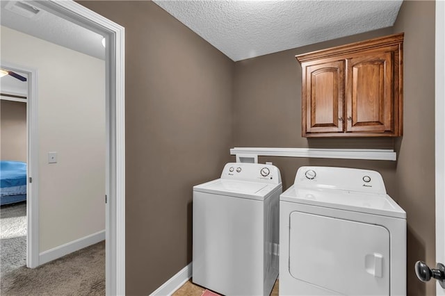 washroom with ceiling fan, cabinets, washing machine and dryer, a textured ceiling, and light carpet