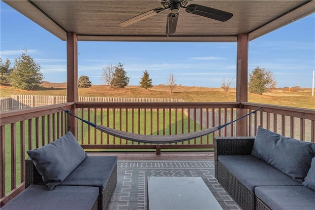 wooden terrace featuring a lawn, outdoor lounge area, ceiling fan, and a rural view