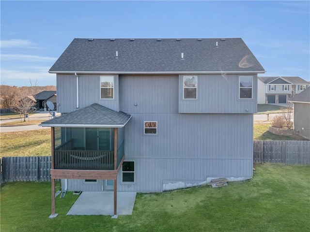 rear view of house featuring a sunroom, a patio, and a lawn