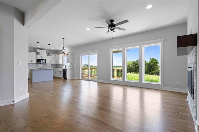 unfurnished living room with ceiling fan and wood-type flooring