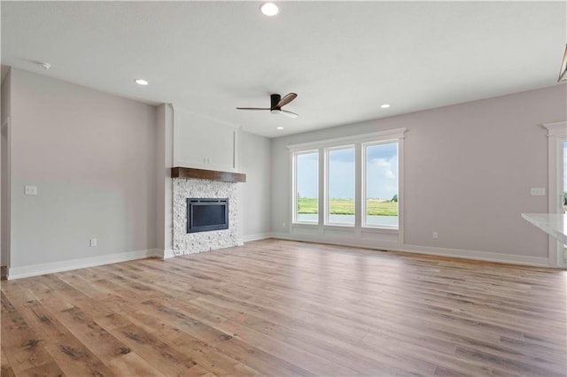 unfurnished living room with light hardwood / wood-style flooring, a fireplace, and ceiling fan