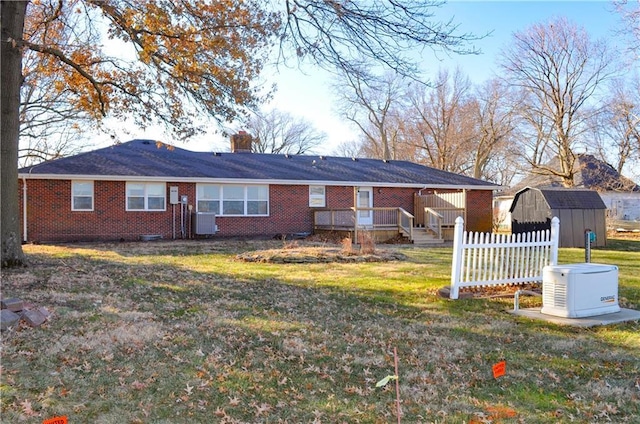 rear view of property featuring a lawn, central air condition unit, and a storage unit