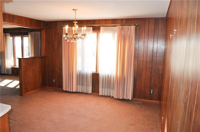 carpeted empty room featuring a wealth of natural light and wood walls