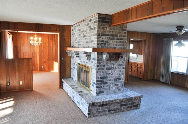 unfurnished living room with wooden walls, a fireplace, and light colored carpet