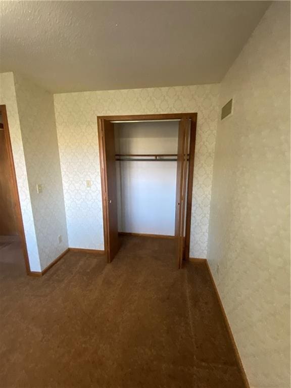 unfurnished bedroom with carpet flooring, a closet, and a textured ceiling