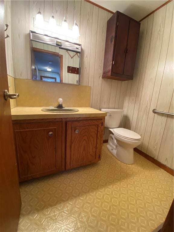 bathroom with vanity, toilet, and wooden walls